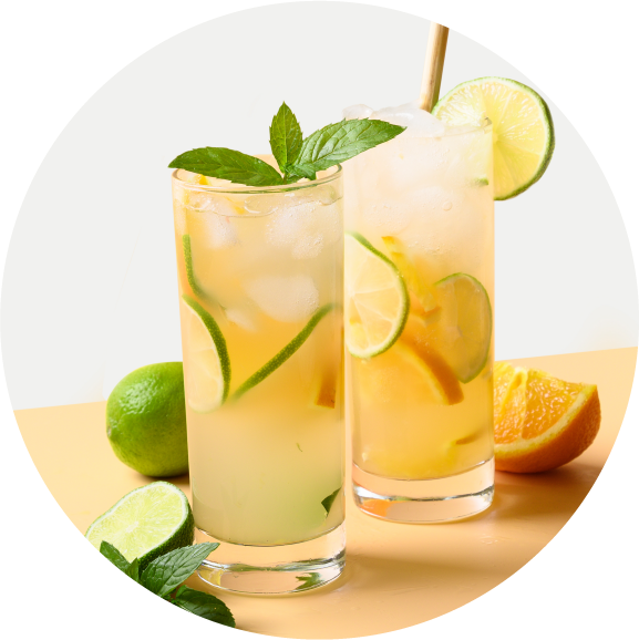 Two tall glasses of iced citrus beverages garnished with lime slices and mint leaves